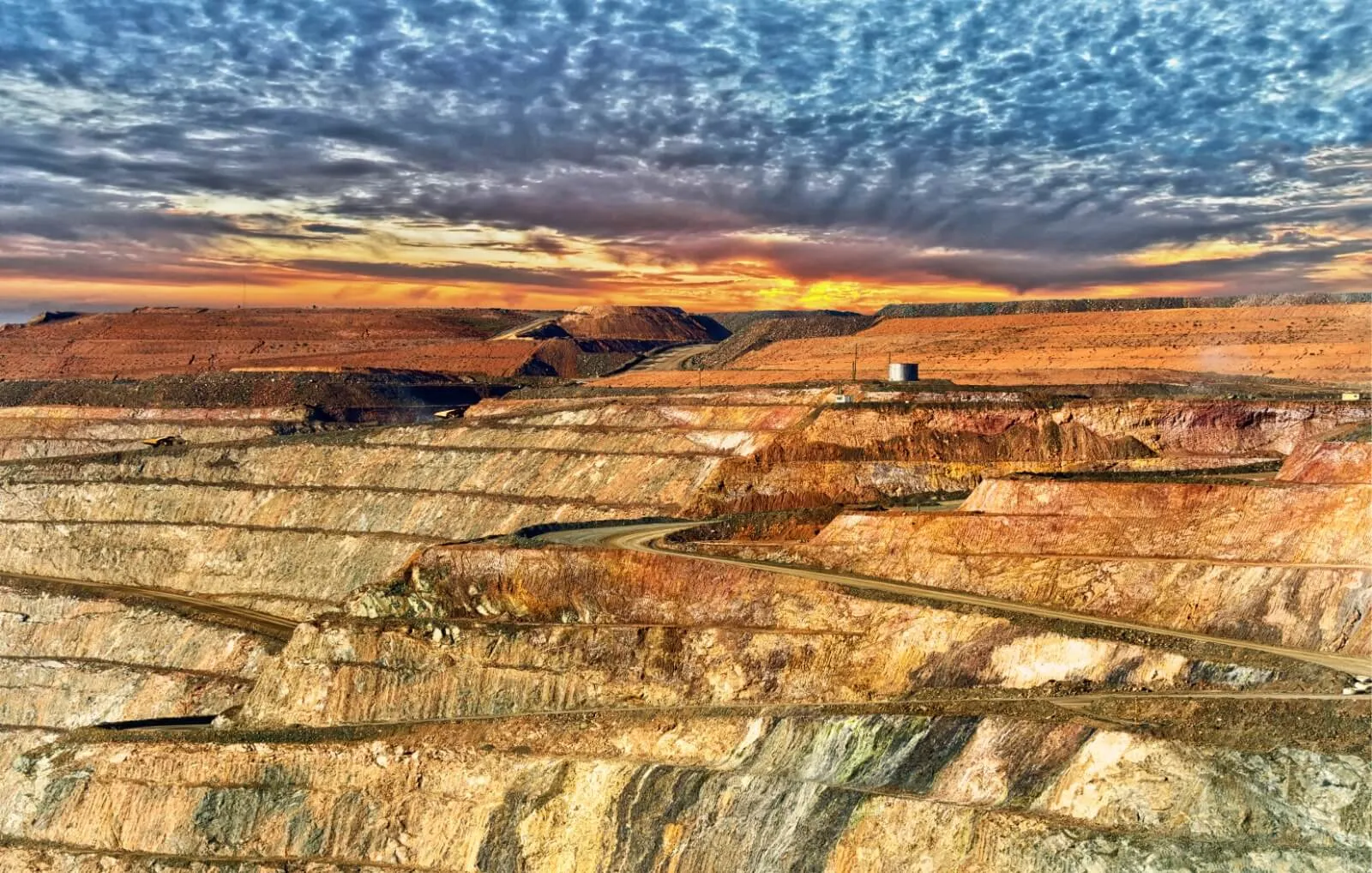 Open cut mine under a dramatic sky at sunset